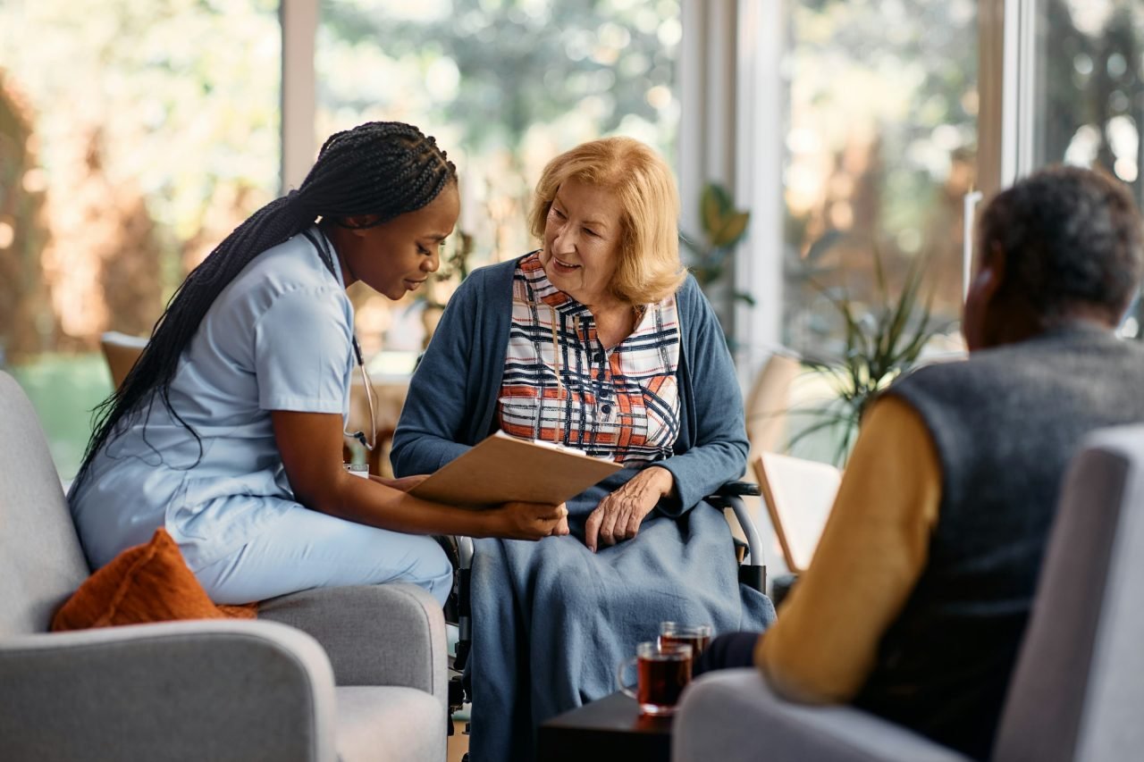 happy senior woman going through her medical data with young nurse at residential care home